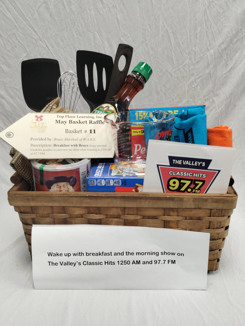 basket with frying pan, 2 spatulas, measuring cup, whisk, pancake mix, 2 bottles of syrup, 2 radio station tee shirts, oatmeal, and stickers.