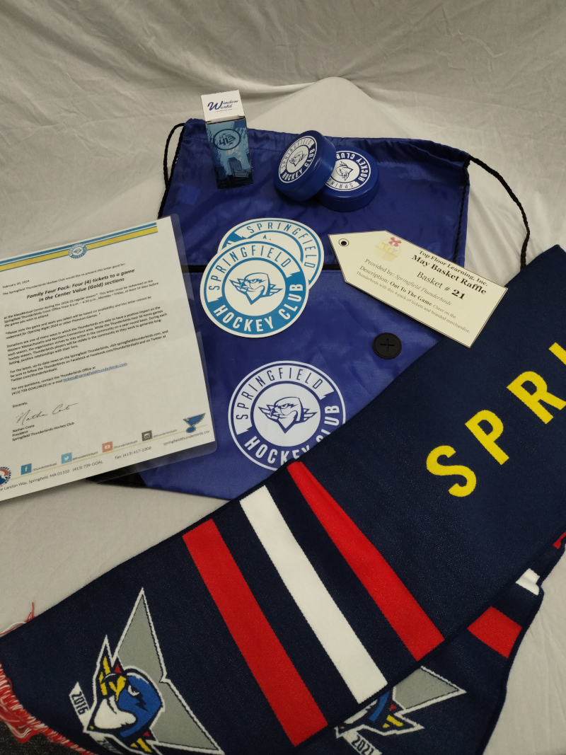 image of a Thunderbirds scarf draped next to a string bag, pucks, stickers, and a laminated letter promising tickets