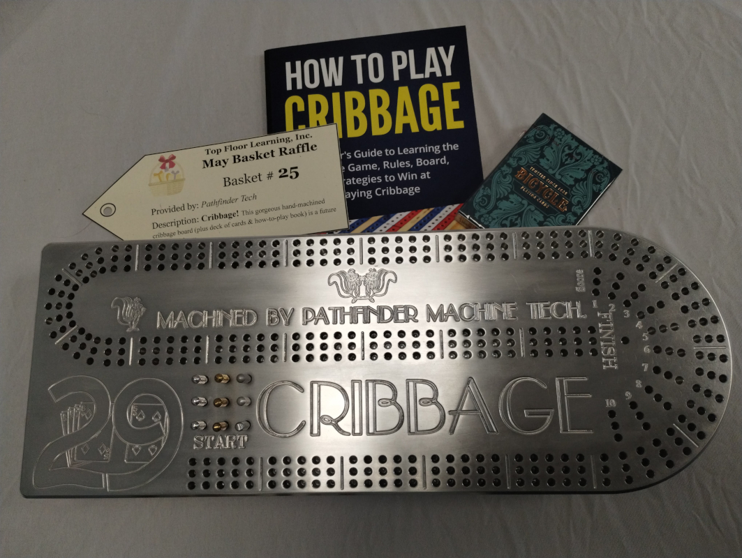 photo of a metal cribbage board machined by the students of Pathfinder Tech, as well as a book on how to play the game and a deck of cards