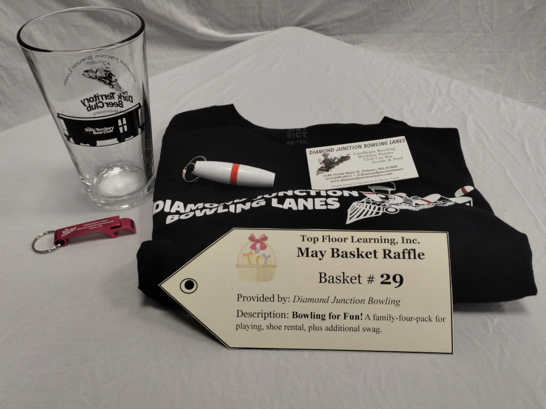 on top of a tee shirt with the bowling lanes' logo is a nice magnet, a candlepin bowling pin keychain, and next to the tee is a branded bottle opener on a keychain and a branded beer glass