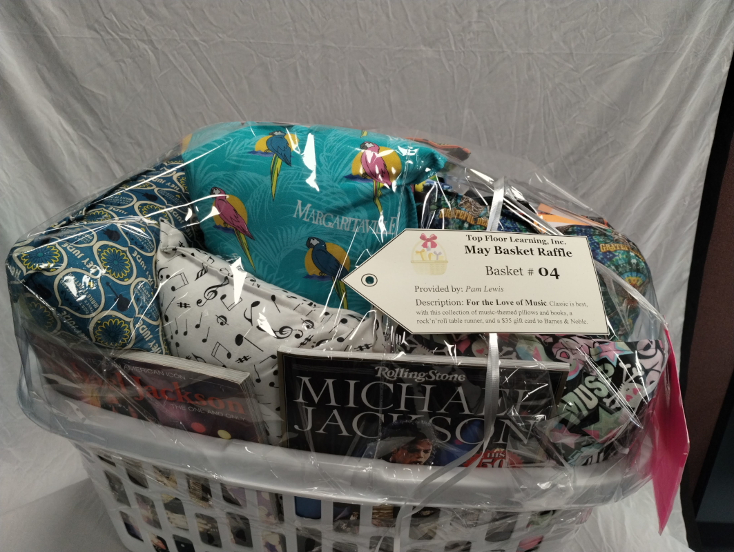 Photograph of a basket stuffed with pillows made of music-themed fabric and music-related books including books on Michael Jackson, David Bowie, and famous musicians.